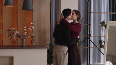 Bir çift, bitkilerle süslü bir iç mekanda sevgi dolu bir kucaklaşmadan hoşlanır..