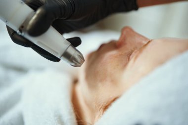 Eğitimli bir uzman, klinikteki bir hastaya deri tedavisi uygular..