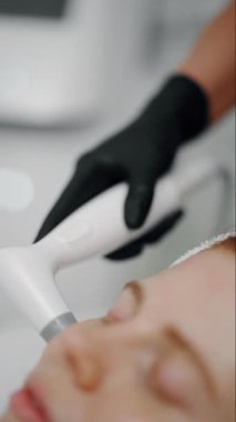 Yenilikçi teknoloji kullanan bir müşterinin yüzünde cilt tedavisi uzmanı