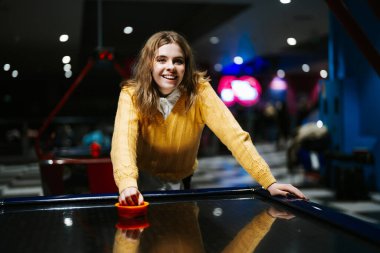 Sarı kazaklı kız oyun salonunda hokey oynuyor..