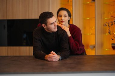 İki insan iyi tasarlanmış bir mutfakta samimi bir anı paylaşır..