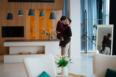 Bir çift, aydınlık bir odada eğlenirken neşeyle kucaklaşır..