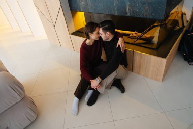 İki insan şık bir şöminenin yanında oturup sıcak bir anı paylaşır..