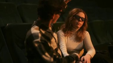 İki birey film izlerken sessiz bir anı paylaşıyor..
