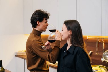 Bir erkek ve kadın bir anı paylaşıyor, sıcak, davetkar mutfaklarında şarabın tadını çıkarıyorlar..