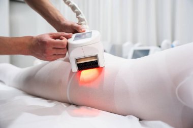 Bir sağlık görevlisi hastaların bacakları üzerinde lazer tedavisi uygular..