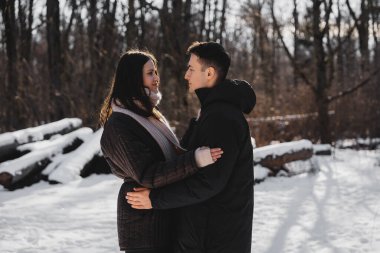 Karla kaplı ağaçlarla çevrili çiftler sıcacık sarılır.