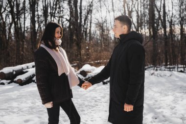 İki insan, karlı bir ormanlık alanda hassas bir etkileşime girer..