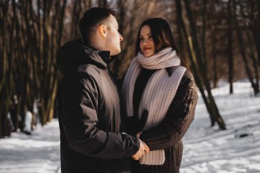 Karlı bir arazide iki insan el ele tutuşup birbirlerine bakıyorlar..