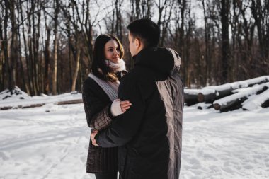 İki birey, karlı ormanda neşeli bir anı paylaşıyor..