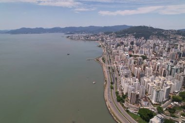 Güneşli bir günde canlı binalar ve sakin sularla kıyı şeridi sergileniyor.