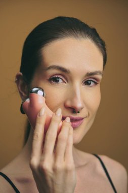 Cilt rutininde bir kadın yanağına yüz gereci uyguluyor..