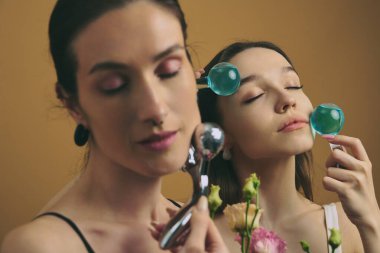 İki kadın yüz gereçleri ve çiçeklerle cilt bakımı yapıyor..