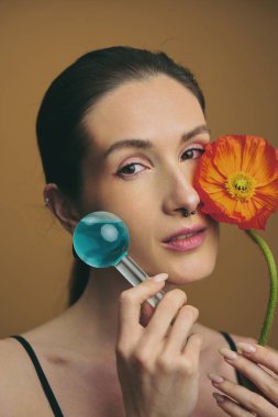 Yüzünde mavi bir alet ve turuncu bir çiçek olan bir kadının yakın çekimi..