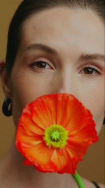 Manken, çarpıcı bir portakal çiçeğiyle yaratıcı bir güzellik gösterisi sunar.