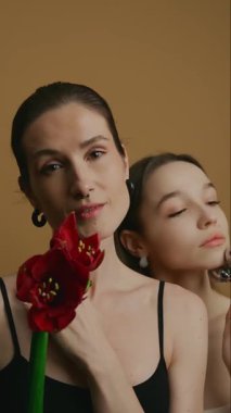 Kadınlar canlı kırmızı çiçekler tutarken zarafet ve güzellik sergilerler..