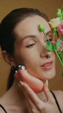 Cilt rutini bir güzellik aleti ve ortam için taze çiçekler içerir.