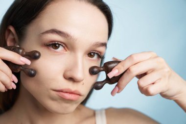 Kadın yüzüne ahşap masaj aletleri kullanıyor, rahatlama tekniklerine odaklanıyor..