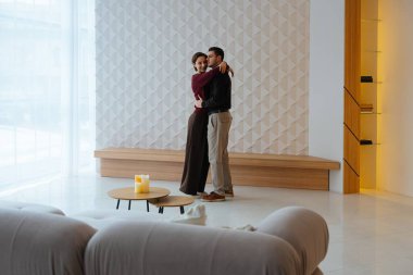 İki birey, çağdaş dekore edilmiş bir alanda sevgiyle kucaklaşır..