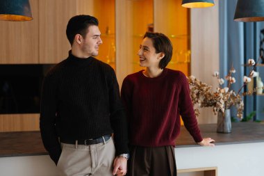 Sıcak, şık bir mutfakta iki insan gülümser..