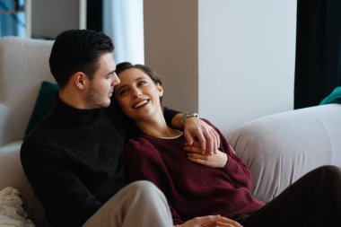 Çift kanepede sarılıyor, kışın gülüşlerini ve sıcaklığını paylaşıyor..