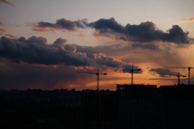Renkli bulutlarla dolu canlı bir günbatımına karşı inşa edilmiş vinçler..