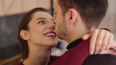 Çift sıcak bir iç mekanda gülümseme ve kahkahalarla kucaklaşır..