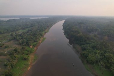 Günbatımında Amazon 'un yoğun bitki örtüsünde bir nehir yavaşça akar..
