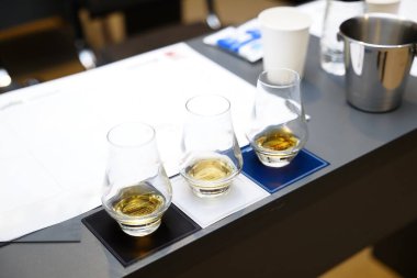 Bir tatma etkinliği sırasında üç bardak viski, şık bir bar masasında dinleniyor..