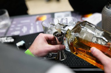 Barmen viskiyi kokteyl yaratmak için ustalıkla ölçüyor..