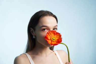 Bir kadın, canlı bir portakal çiçeğiyle poz vererek güzelliğini gösterir..