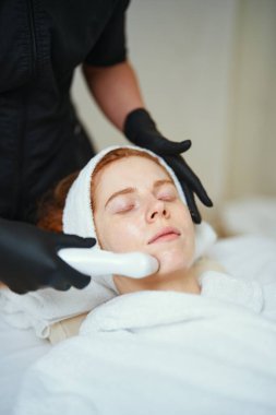 Genç bir kadın kaplıcada yüz bakımı yaparken rahatlıyor..