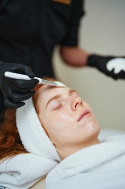 Bir kadın spa 'da bir profesyonel tarafından uygulanan yüz tedavisinden hoşlanır..