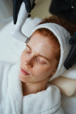 Rahat kadın, sakin bir spa ortamında yüz bakımı yaptırıyor..