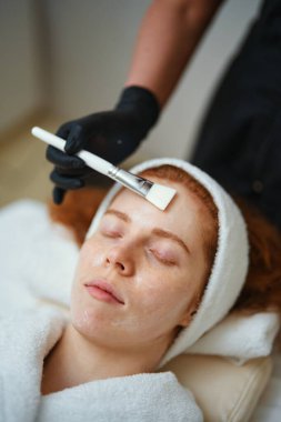 Güzellik uzmanı kaplıcaya yüz maskesi takarken bir kadın rahatlar..