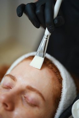 Becerikli bir işçi müşterisinin cildine yüz bakımı uygular..