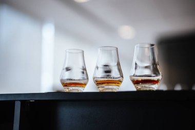 Üç bardak viski vitrini şık bir ortamda zengin bir kehribar rengi.