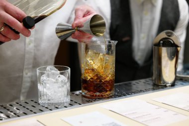 Barmen ustalıkla buzlu küplerin üzerine zengin bir içki koyar..