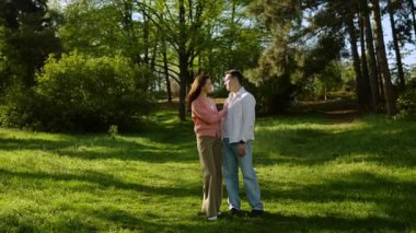 Mutlu bir çift, güneşin altındaki canlı bir parkta neşeli bir kucaklaşmayı paylaşır..