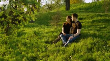Aşıklar, çimenli bir yamaçta dinlenirken samimi anlar paylaşırlar..