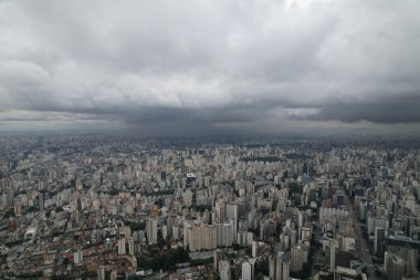 Sao Paulo üzerinde bulutlu bir gökyüzü beliriyor, geniş bir şehir manzarası sergiliyor..