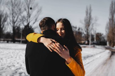 İki insan, kışın ortasında sevgi dolu bir kucaklaşmayı paylaşıyor..