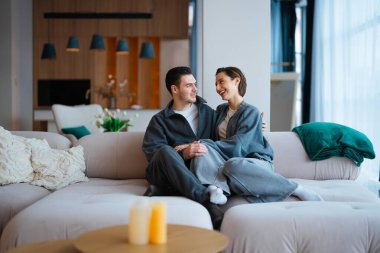 Neşeli çift kanepeye yakın oturuyor, sıcaklığı ve kahkahaları içeride paylaşıyorlar..