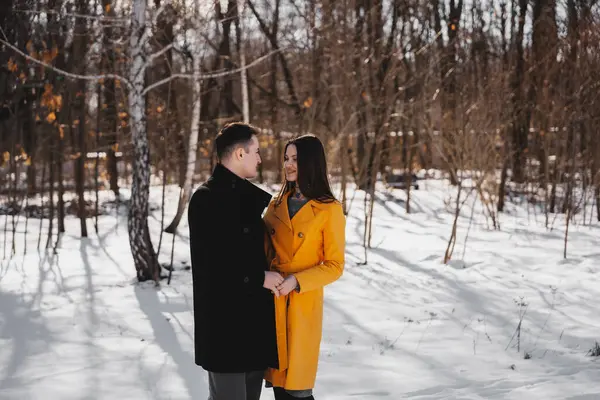 Genç çift, karlı bir ormanda birlikte, kış havasının tadını çıkarıyor..