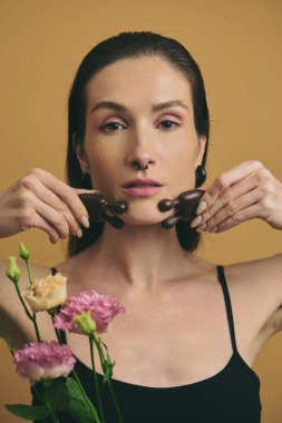 Modellerde bir buket çiçek tutarken ahşap masaj aletleri sergilenir.