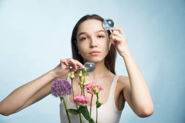 Gözlem için büyüteç kullanan kadın çiçekleri tutuyor..