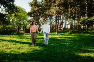 İki birey, doğadaki yemyeşil ağaçların arasında huzurlu bir yürüyüşün tadını çıkarıyor..