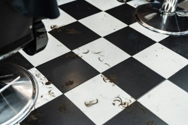 Kesiklerle dolu bir günün ardından şık bir salonun zemininde saç kesikleri var..