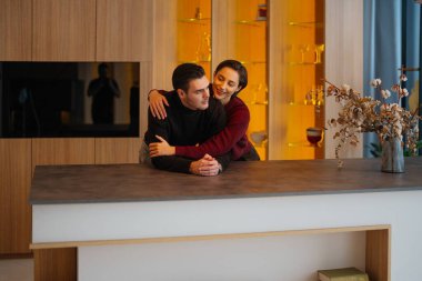 İki insan evlerindeki modern mutfak tezgahında sıcak bir anı paylaşıyor..