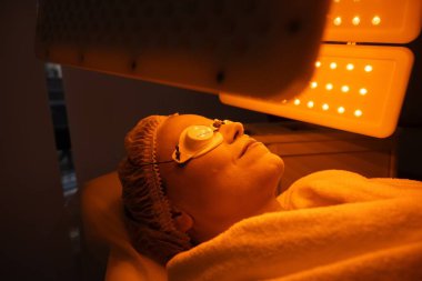 Müşteri cilt bakımı için terapi seansı sırasında parlak ışık altında dinlenir.